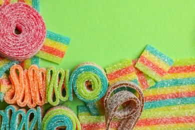 Photo of Different tasty sour belts on green background, flat lay