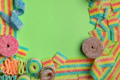 Photo of Different tasty sour belts on green background, flat lay. Space for text