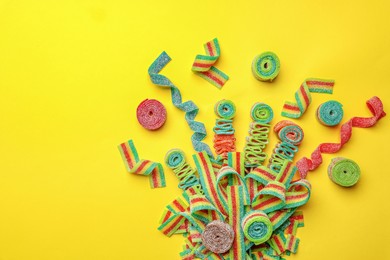 Photo of Different tasty sour belts on yellow background, flat lay. Space for text