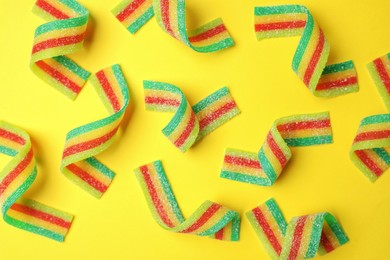 Photo of Tasty rainbow sour belts on yellow background, top view