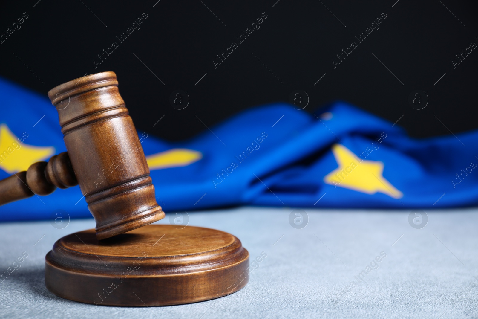 Photo of Judge's gavel and European Union flag on light textured table against black background, closeup. Space for text