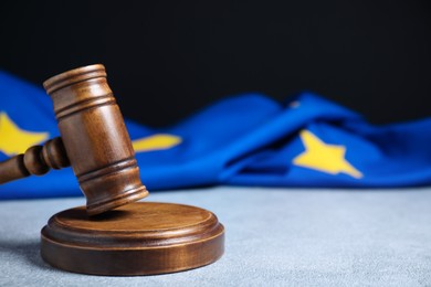 Photo of Judge's gavel and European Union flag on light textured table against black background, closeup. Space for text