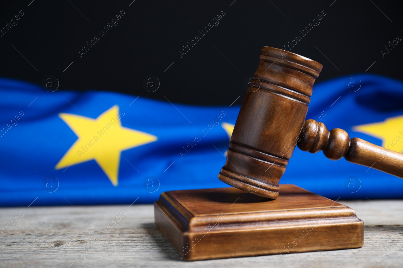 Photo of Judge's gavel and European Union flag on wooden table against black background, closeup. Space for text