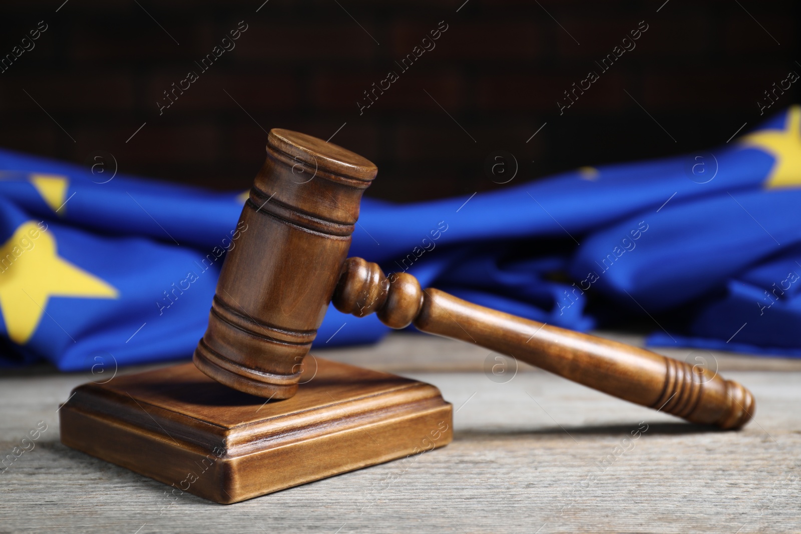 Photo of Judge's gavel and European Union flag on wooden table against black background, closeup