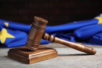 Photo of Judge's gavel and European Union flag on wooden table against black background, closeup