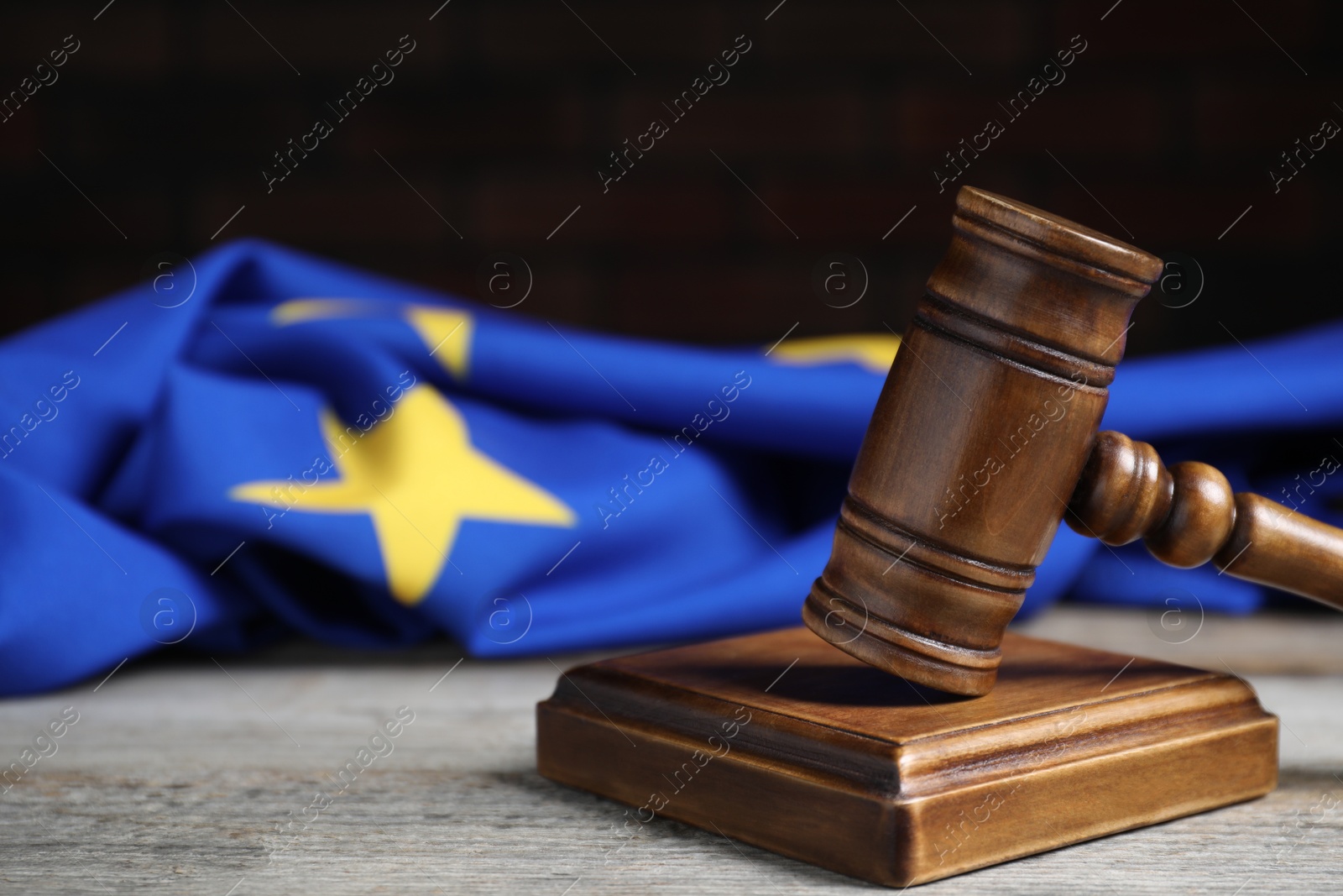 Photo of Judge's gavel and European Union flag on wooden table against black background, closeup. Space for text