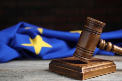 Photo of Judge's gavel and European Union flag on wooden table against black background, closeup. Space for text