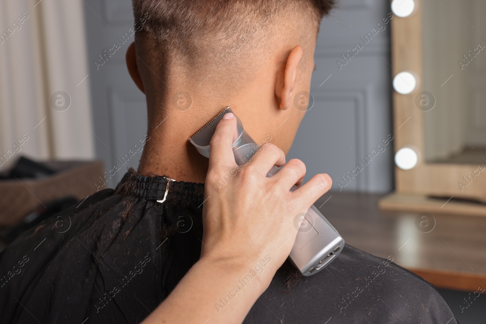 Photo of Professional barber making stylish haircut in salon, closeup