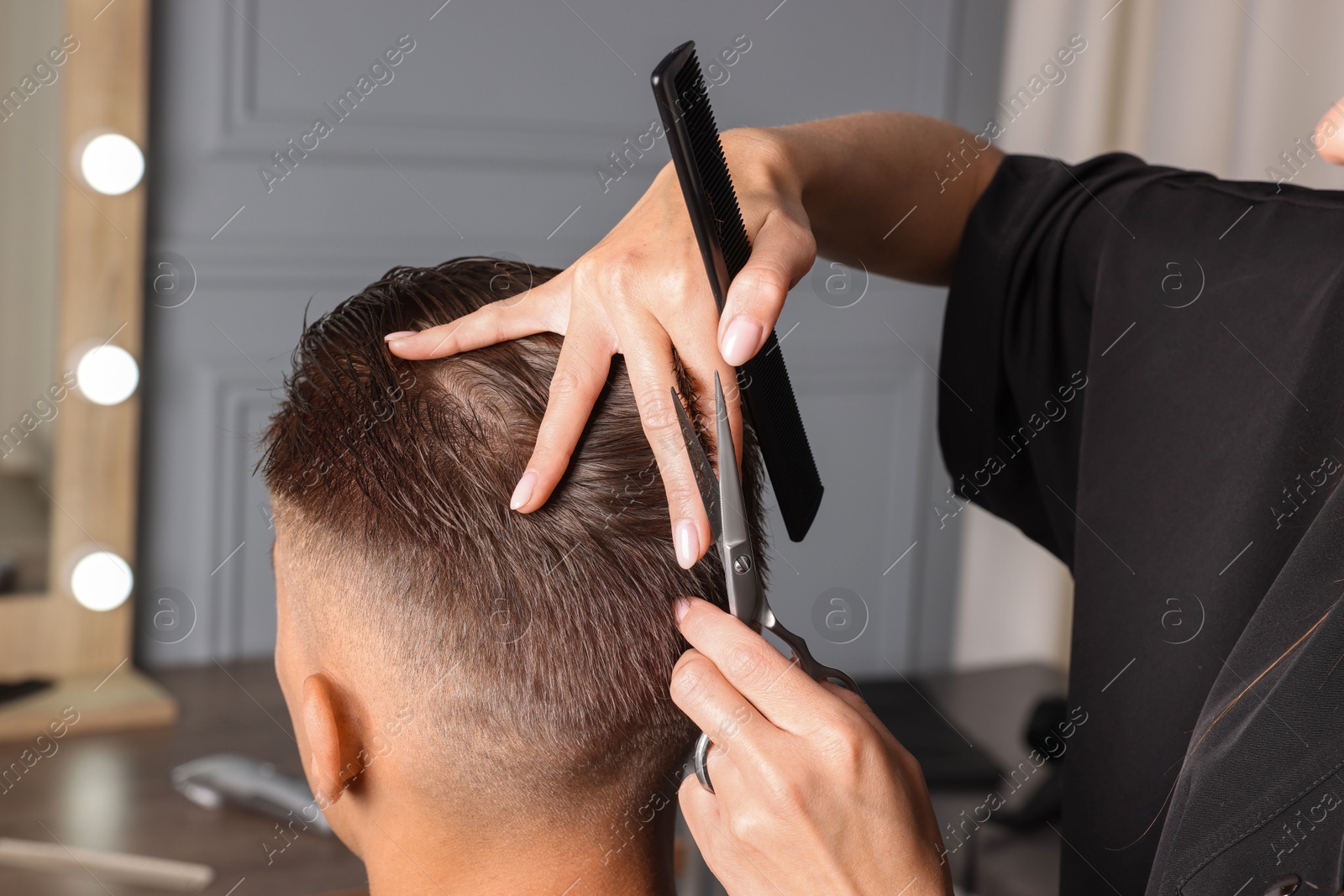 Photo of Professional hairdresser cutting client's hair with scissors in barbershop, closeup