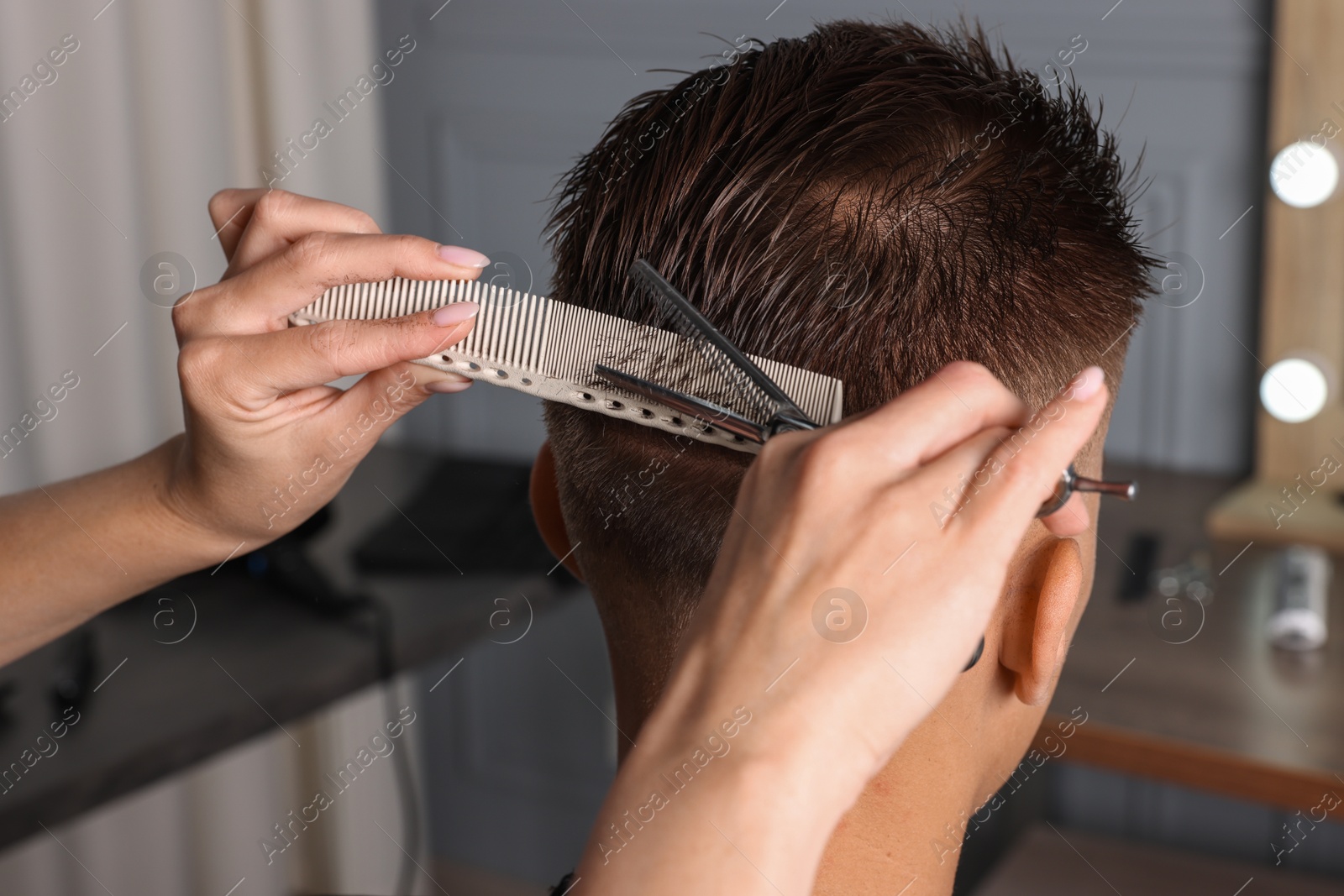 Photo of Professional hairdresser cutting client's hair with scissors in barbershop, closeup