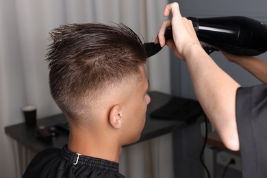 Photo of Hairdresser blow drying client's hair in barbershop, closeup