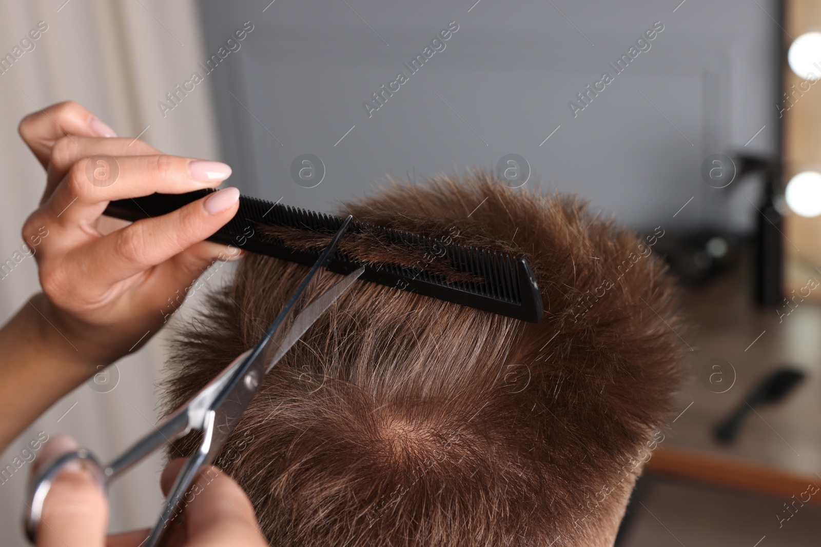 Photo of Professional hairdresser cutting client's hair with scissors in barbershop, closeup