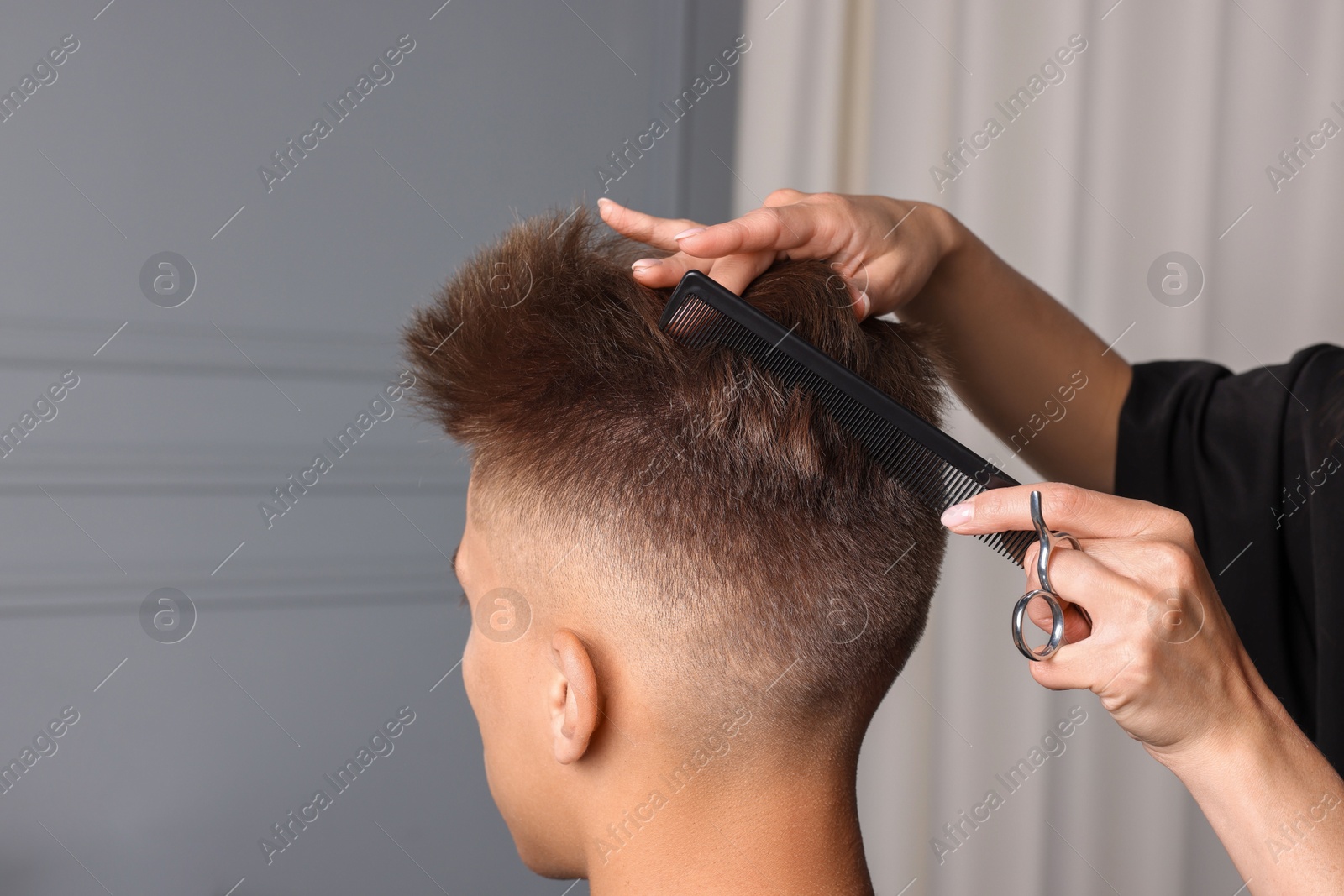 Photo of Professional barber making stylish haircut in salon, closeup