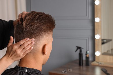 Photo of Hair cutting. Professional hairdresser working with client in barbershop, closeup. Space for text