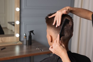 Photo of Hair cutting. Hairdresser combing man's hair in barbershop, closeup