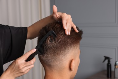 Photo of Hair cutting. Hairdresser combing man's hair in barbershop, closeup