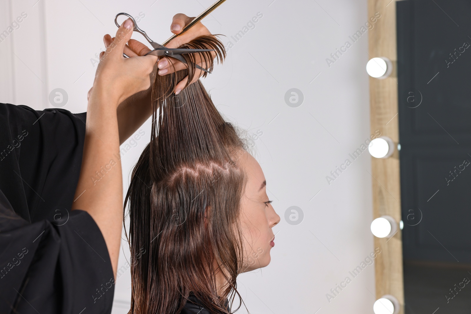 Photo of Hairdresser cutting client's hair with scissors in salon, closeup