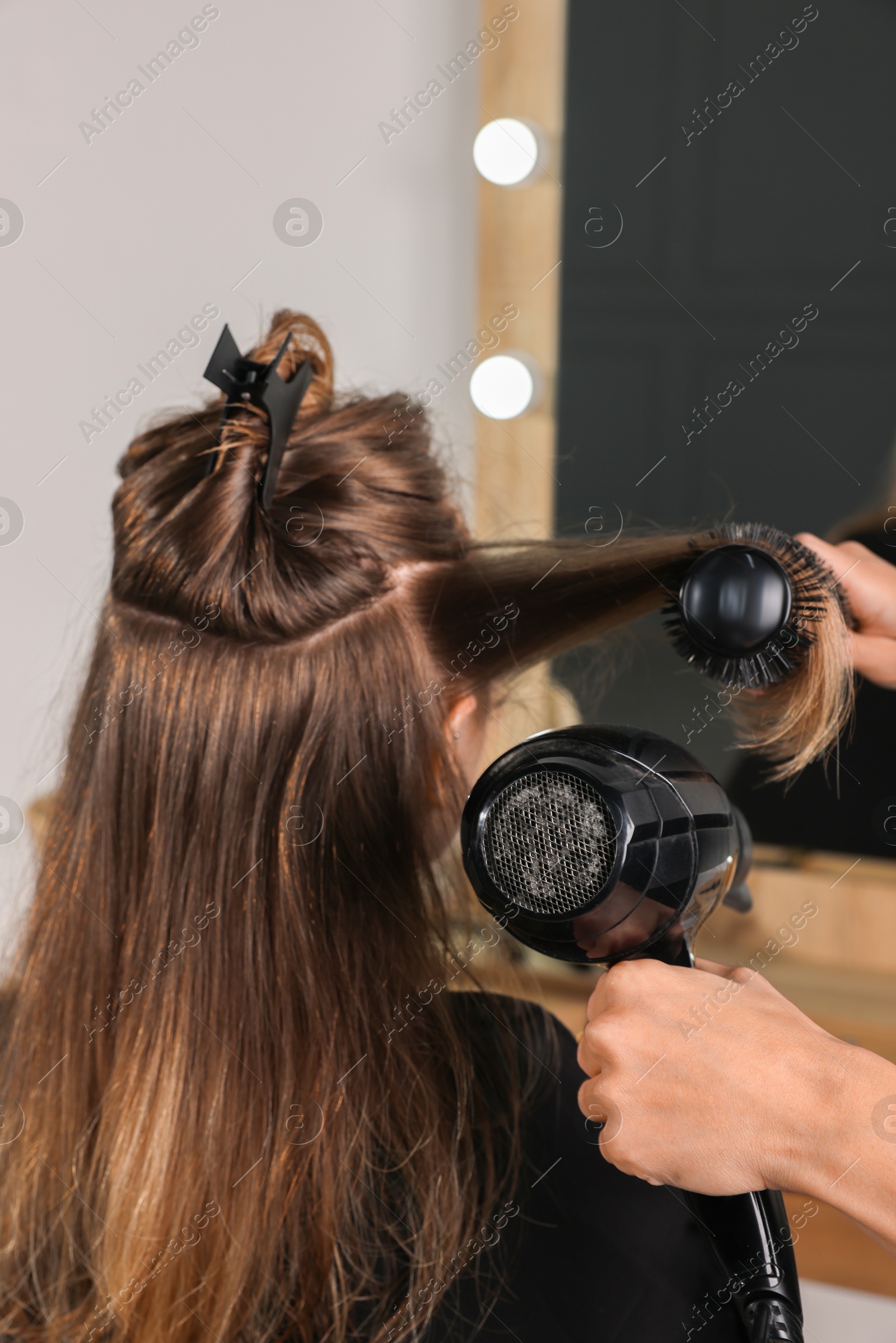 Photo of Hairdresser blow drying client's hair in salon, closeup