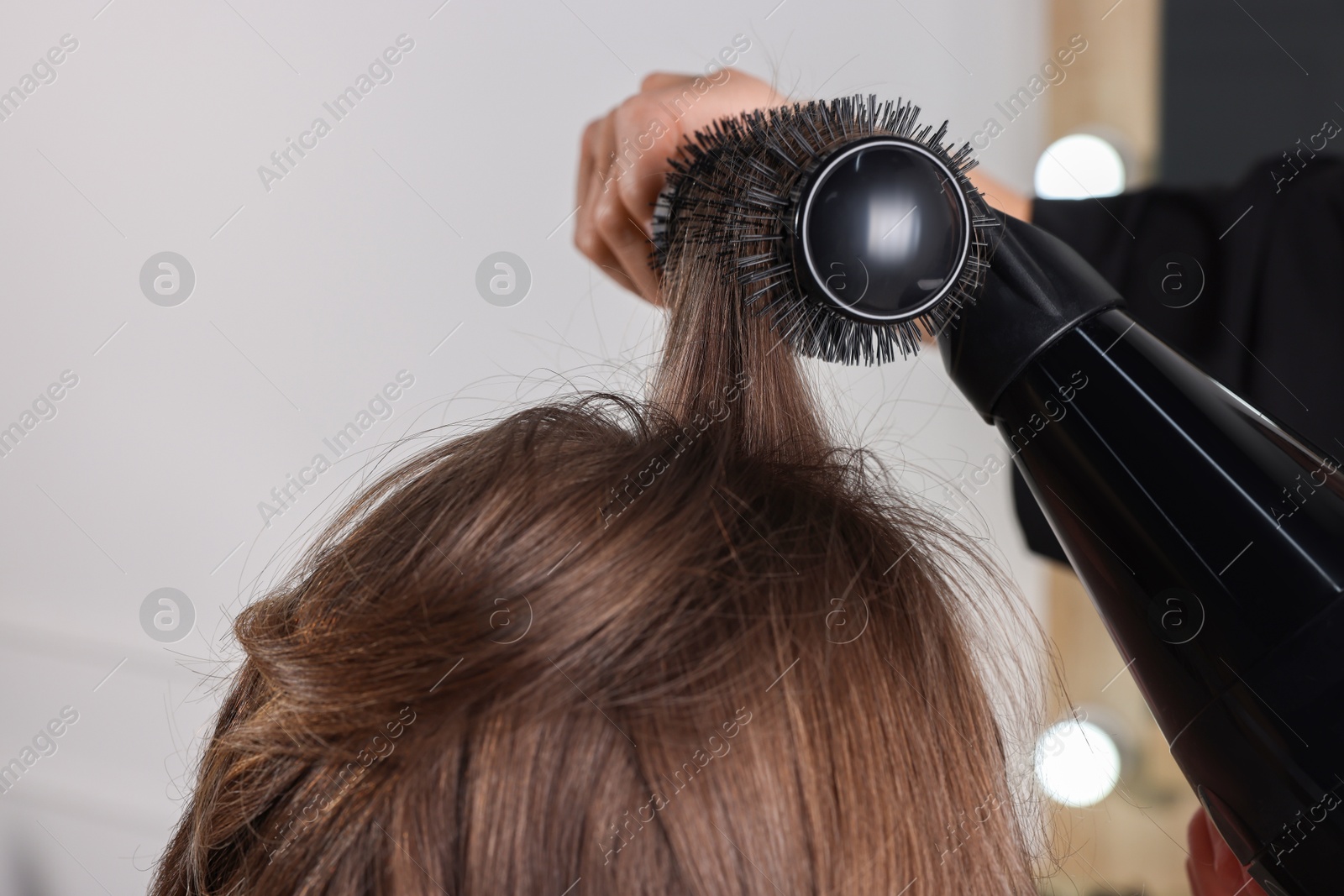 Photo of Hairdresser blow drying client's hair in salon, closeup