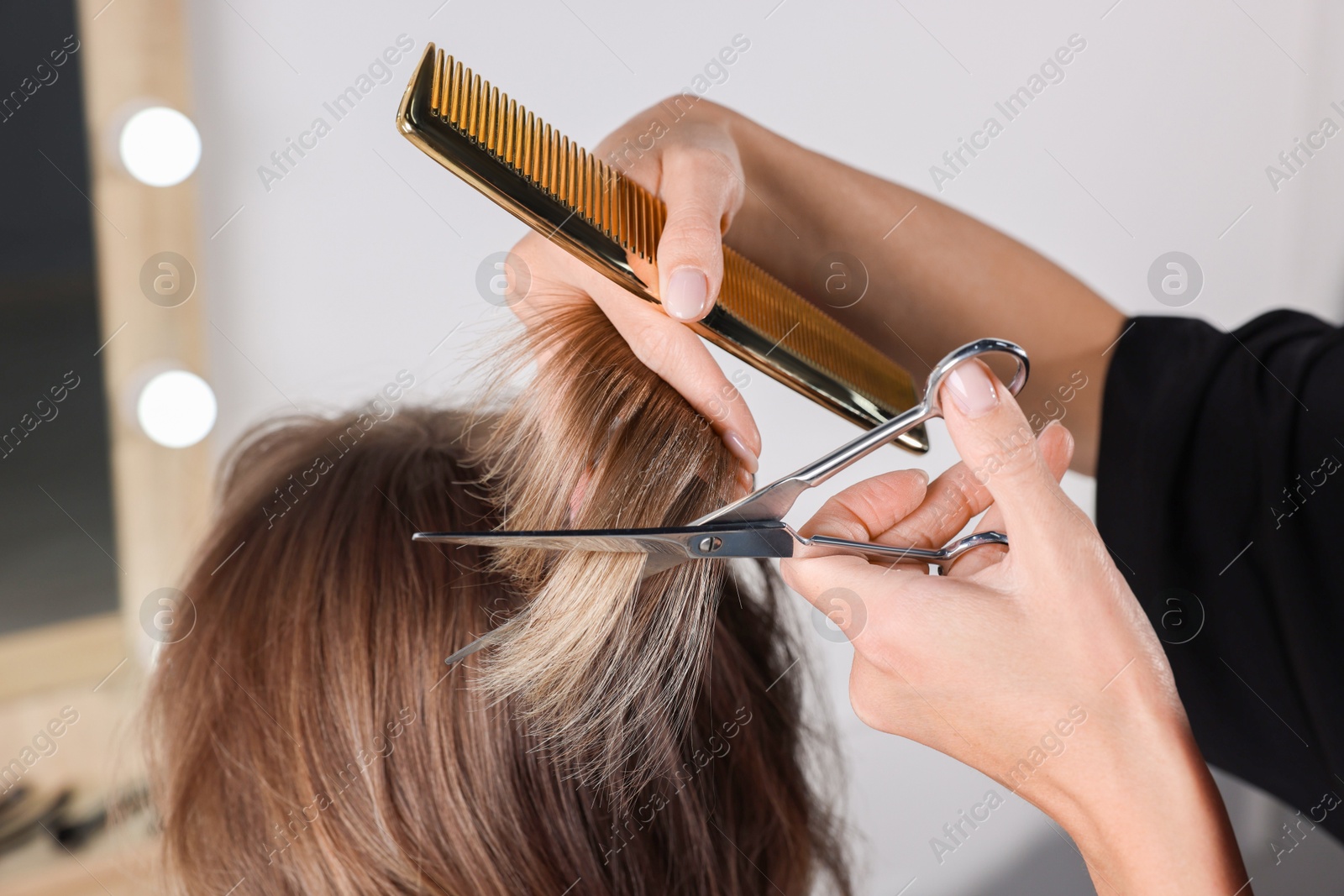 Photo of Hairdresser cutting client's hair with scissors in salon, closeup