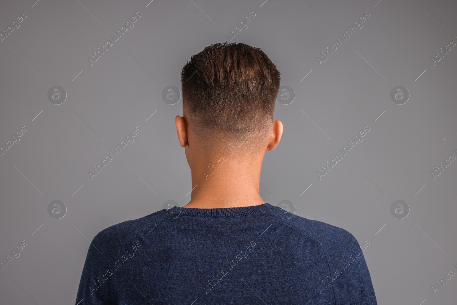 Photo of Man with stylish haircut on grey background, back view