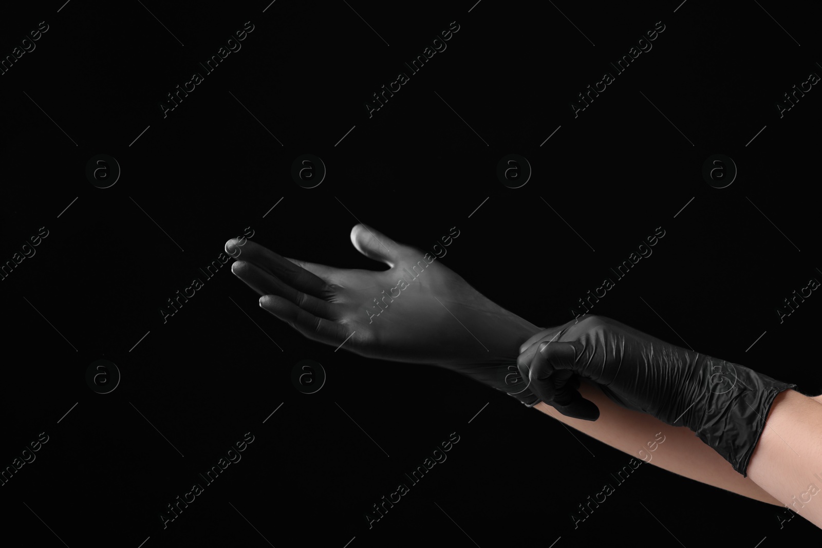 Photo of Man wearing latex gloves on black background, closeup