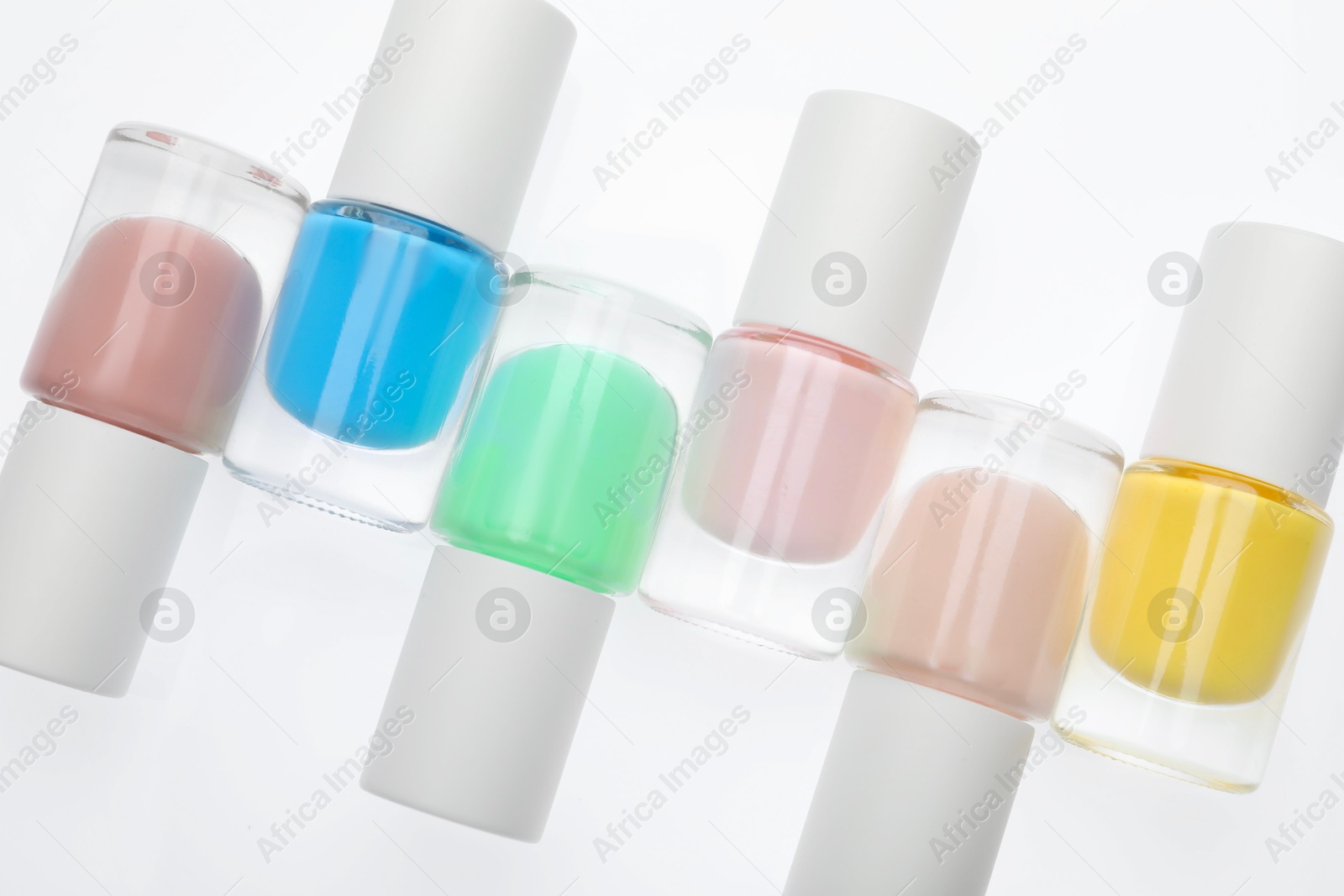 Photo of Nail polishes in bottles on white background, top view