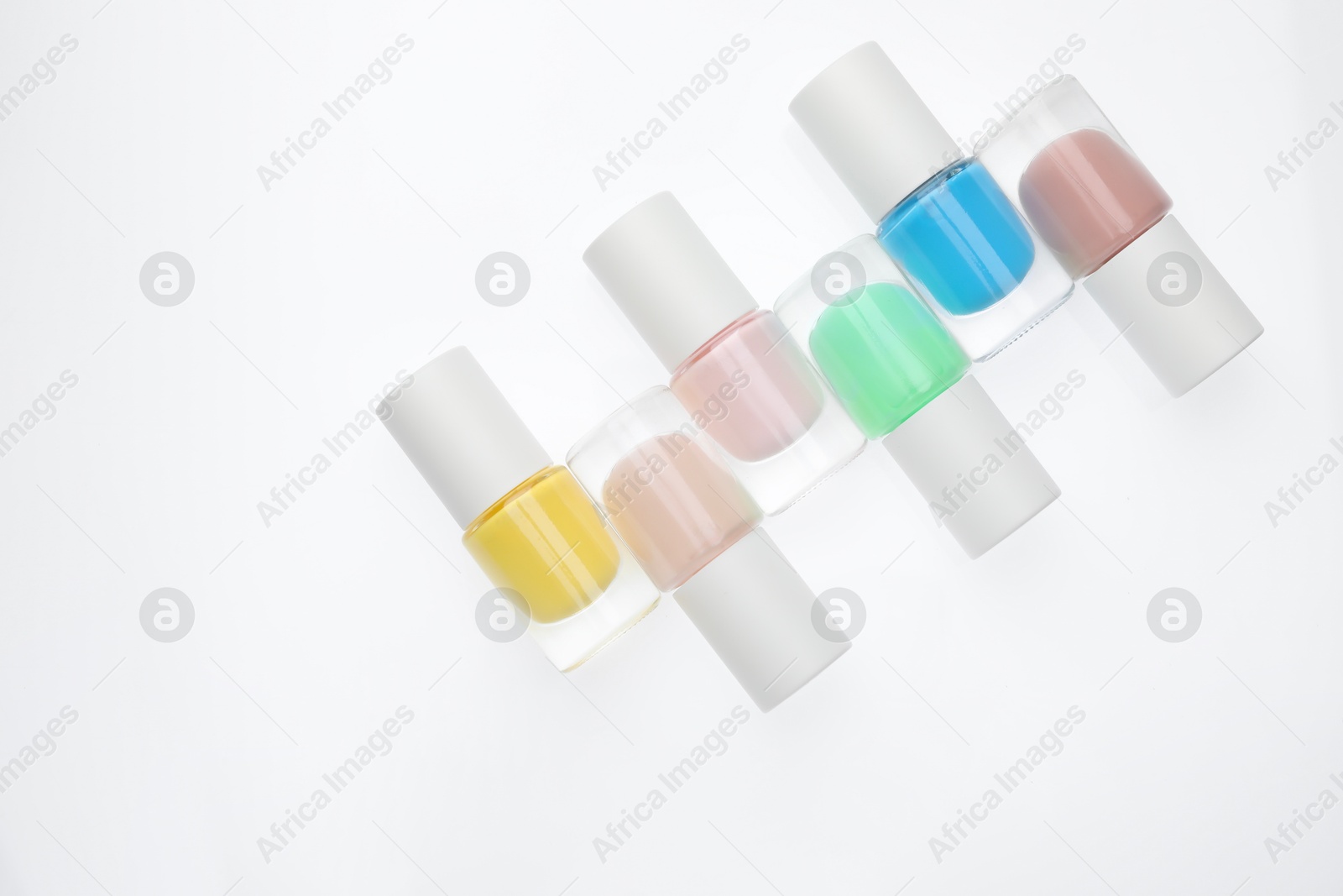 Photo of Nail polishes in bottles on white background, top view. Space for text