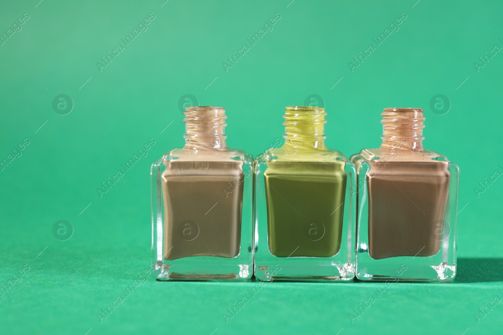 Photo of Nail polishes in bottles on green background