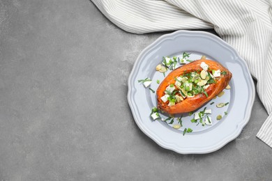 Photo of Tasty cooked sweet potato with feta cheese, pumpkin seeds and green onion on grey table, top view. Space for text