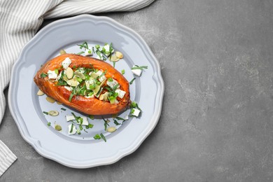 Photo of Tasty cooked sweet potato with feta cheese, pumpkin seeds and green onion on grey table, top view. Space for text