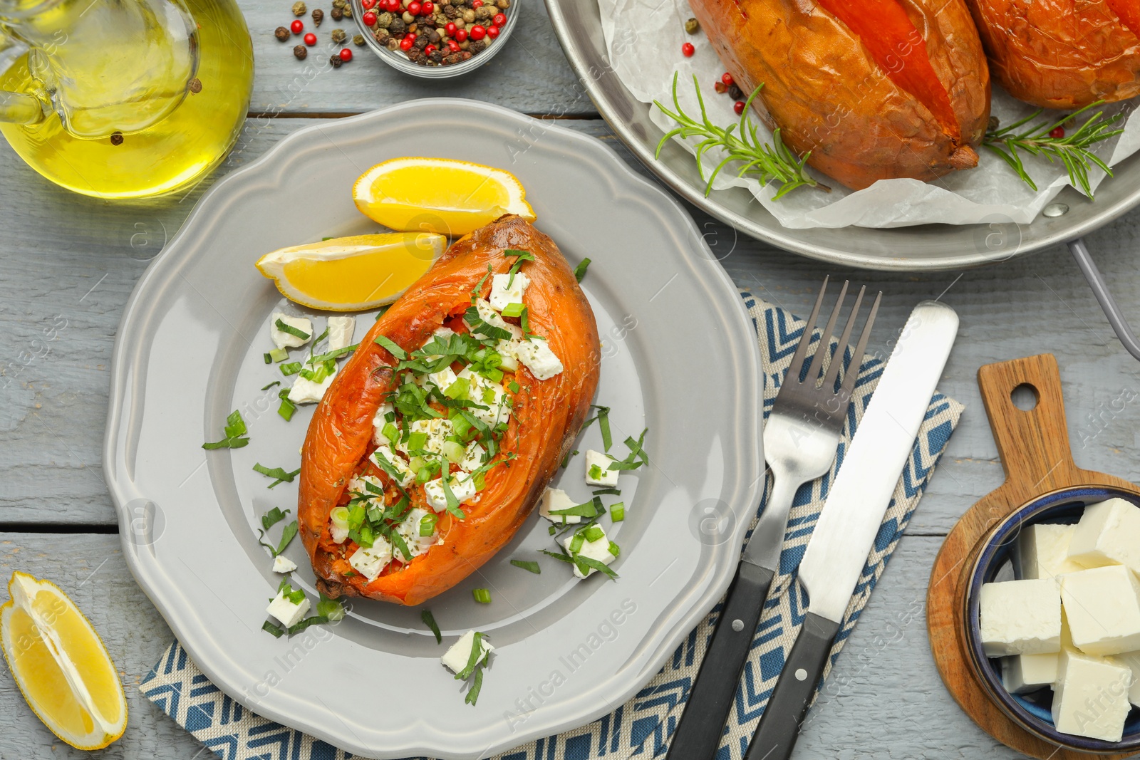 Photo of Tasty cooked sweet potatoes served with feta cheese on grey wooden table, top view