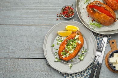 Photo of Tasty cooked sweet potatoes served with feta cheese on grey wooden table, top view. Space for text