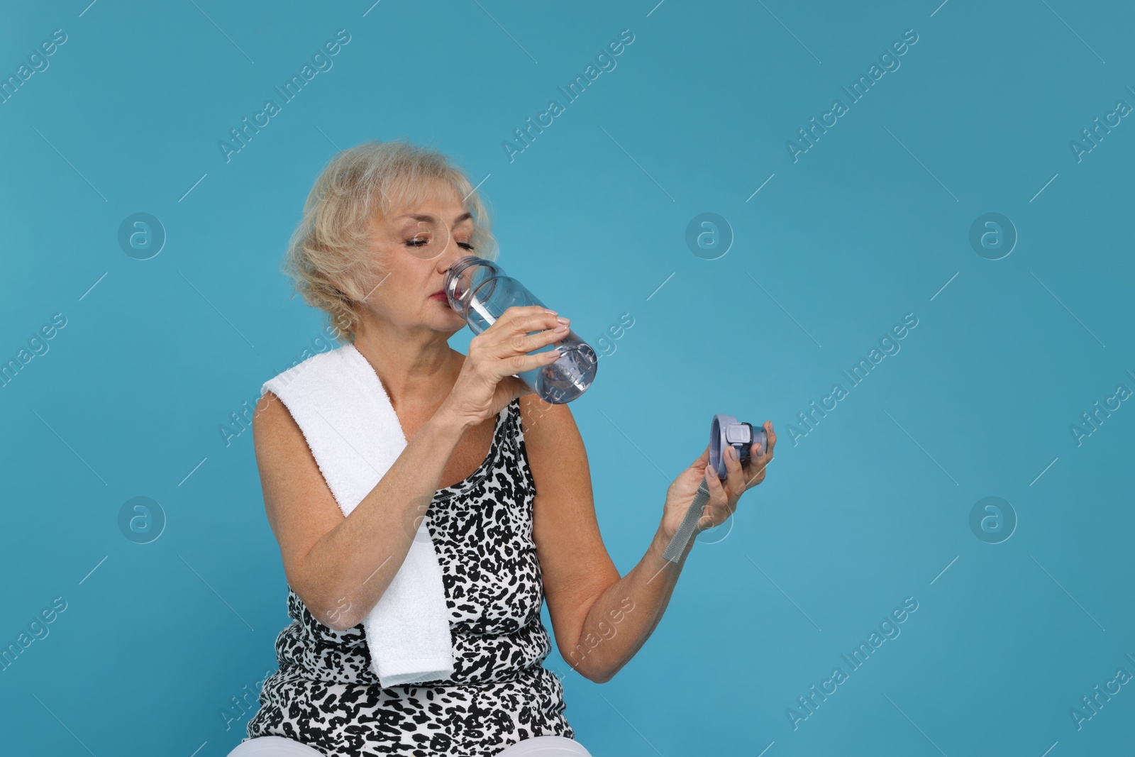 Photo of Senior woman with towel and water on light blue background. Space for text