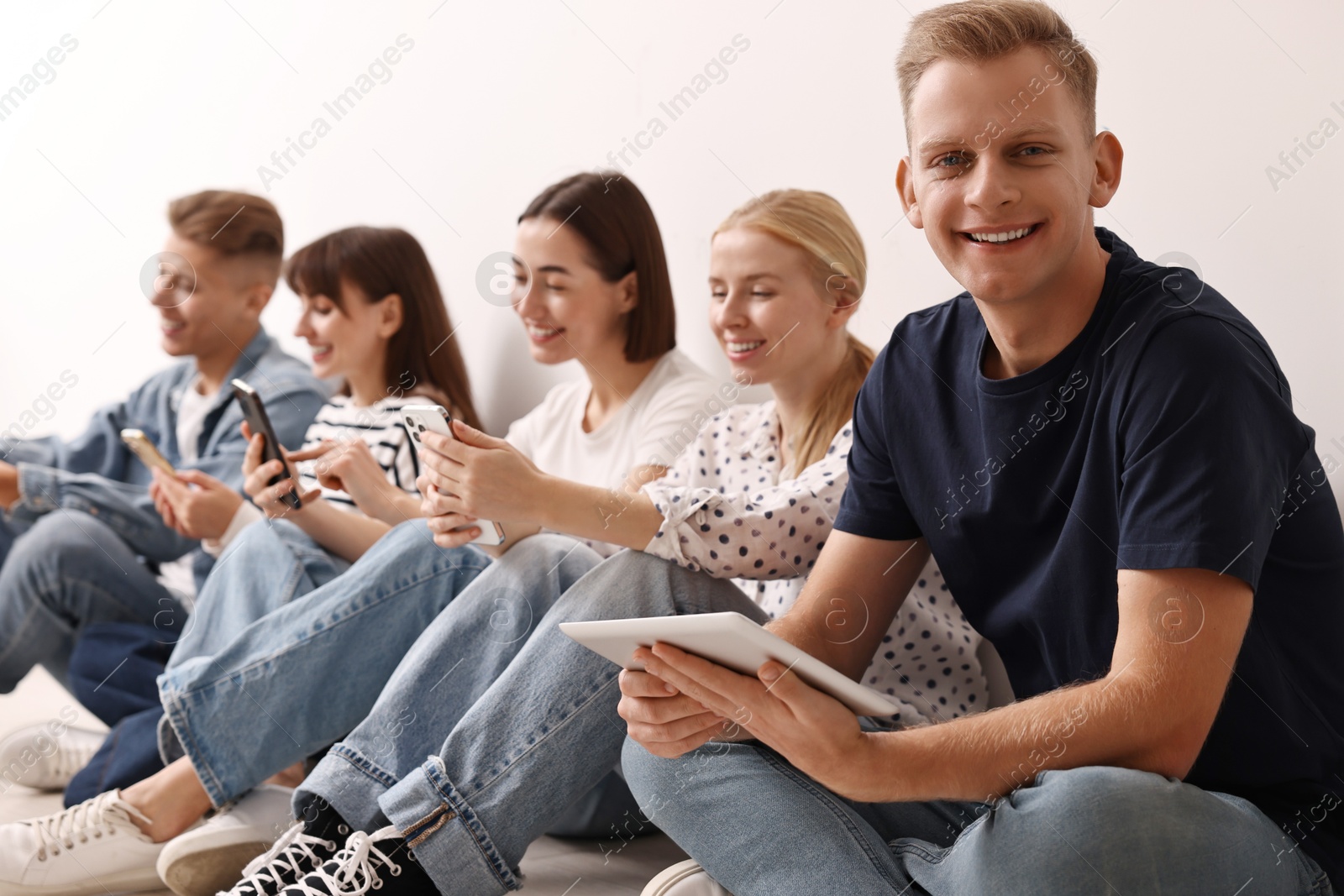 Photo of Group of people using different gadgets on floor indoors. Modern technology