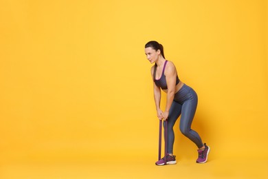 Photo of Beautiful woman with resistance band training on yellow background. Space for text