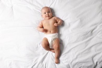 Photo of Cute little baby in diaper on bed, top view