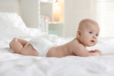 Photo of Cute little baby in diaper on bed indoors