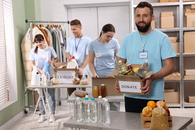 Photo of Group of volunteers packing donation goods at tables indoors