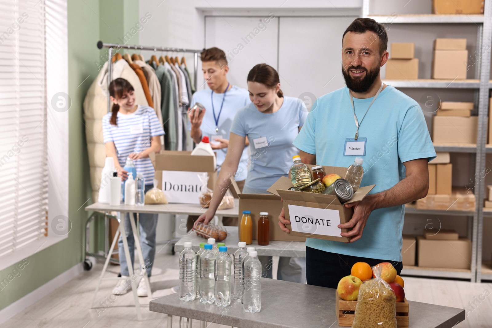 Photo of Group of volunteers packing donation goods at tables indoors