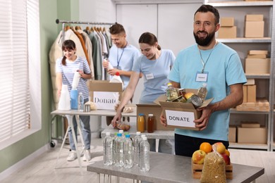 Photo of Group of volunteers packing donation goods at tables indoors