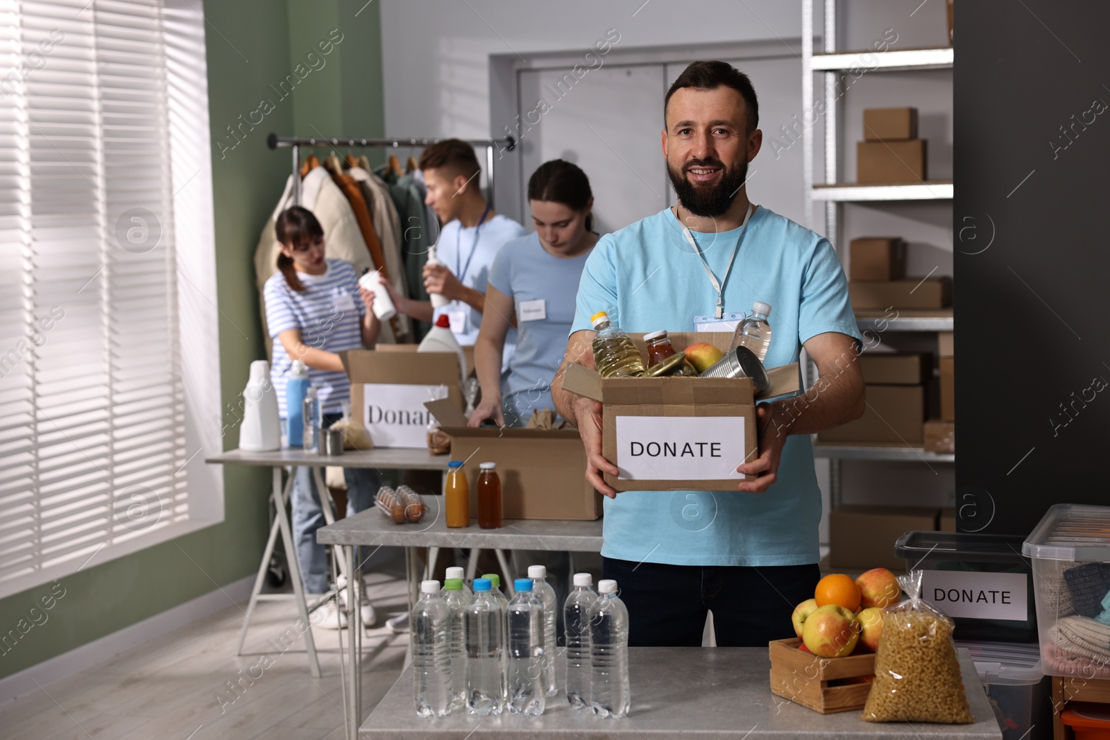 Photo of Group of volunteers packing donation goods at tables indoors