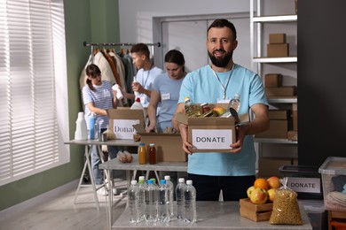 Photo of Group of volunteers packing donation goods at tables indoors