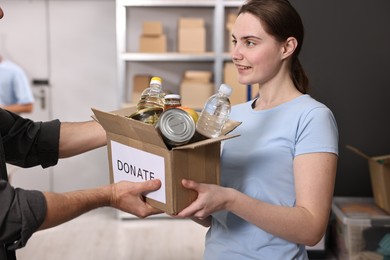 Photo of Volunteers holding donation box with food products indoors