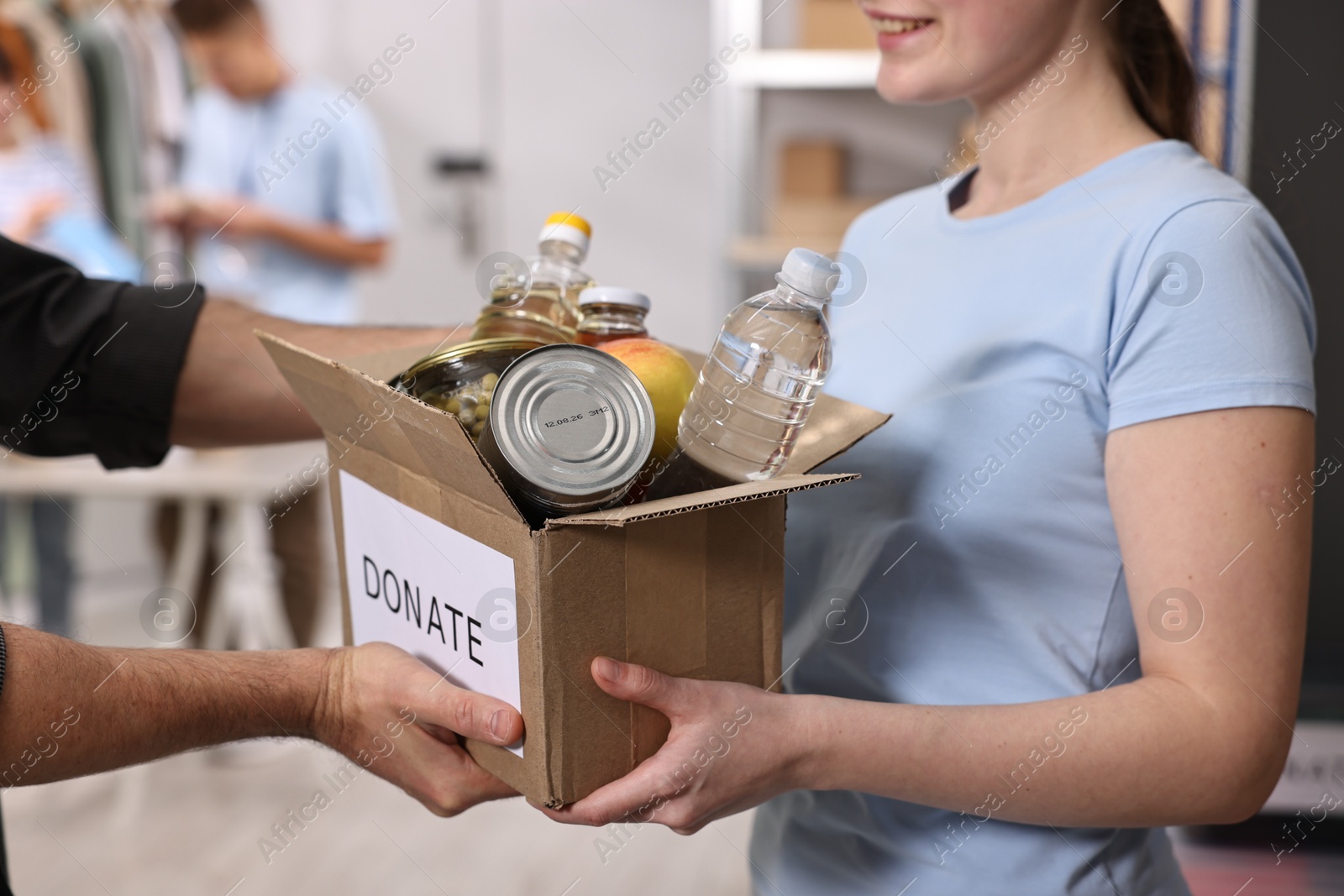 Photo of Volunteers holding donation box with food products indoors, closeup