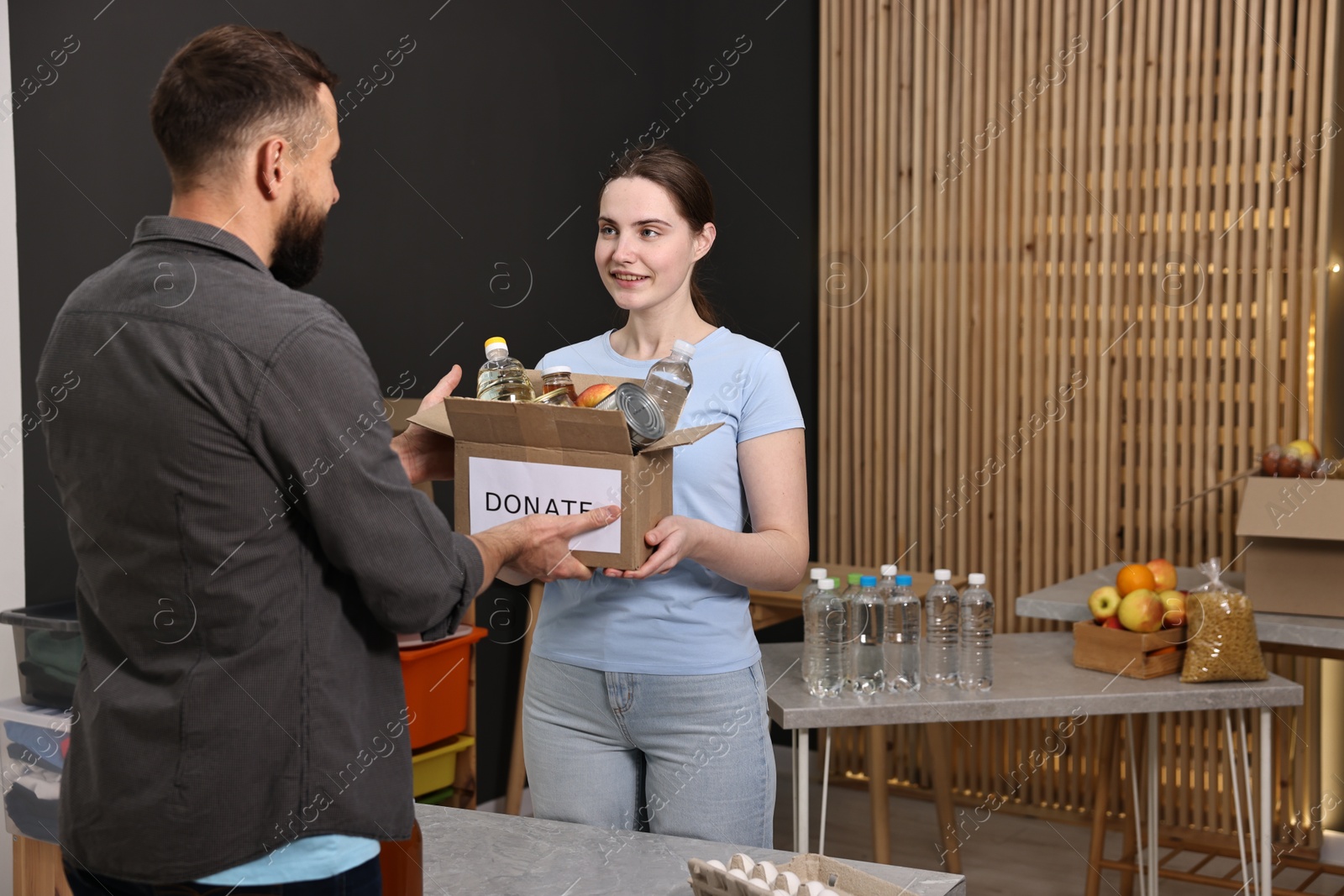 Photo of Volunteers holding donation box with food products indoors