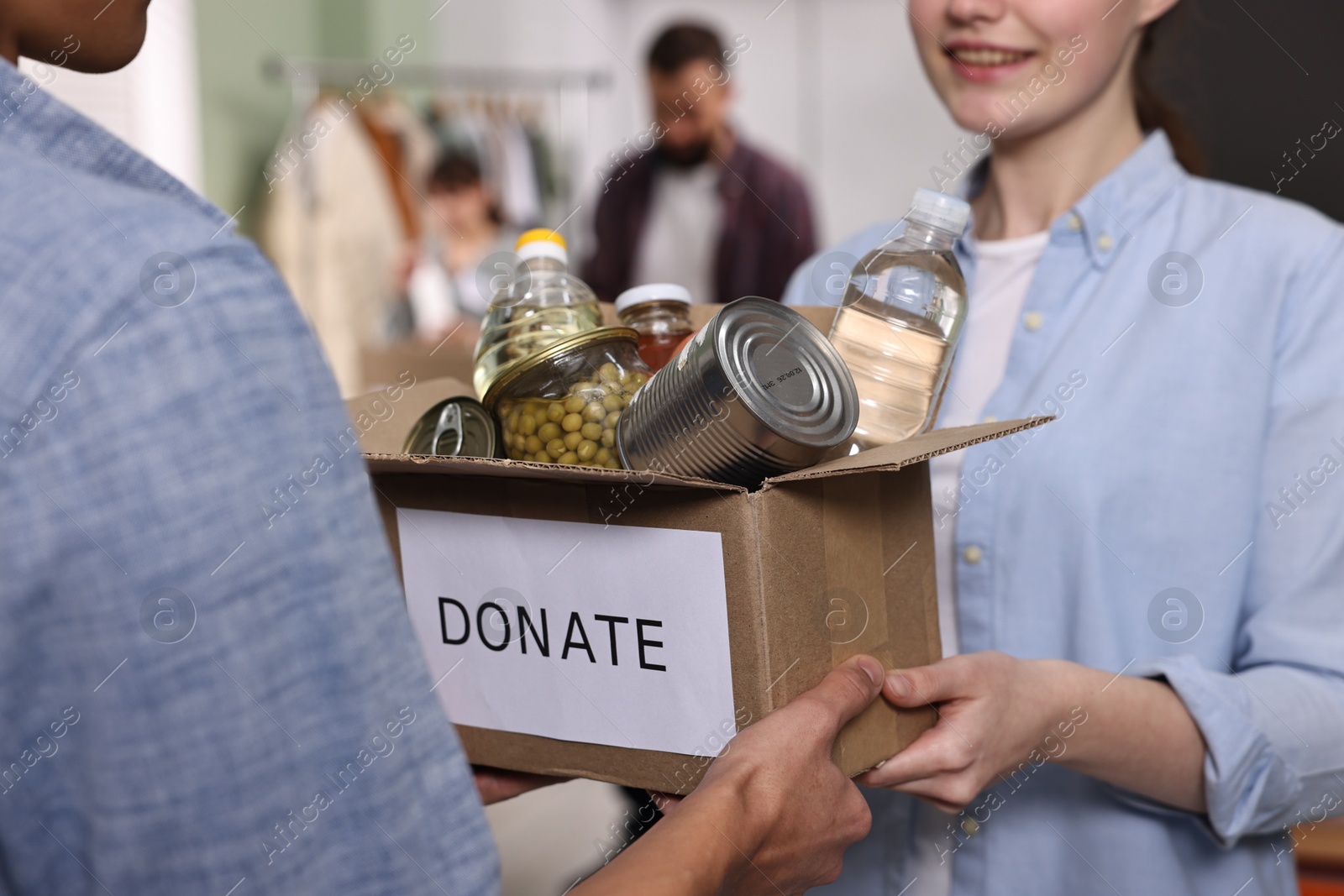 Photo of Volunteers holding donation box with food products indoors, closeup