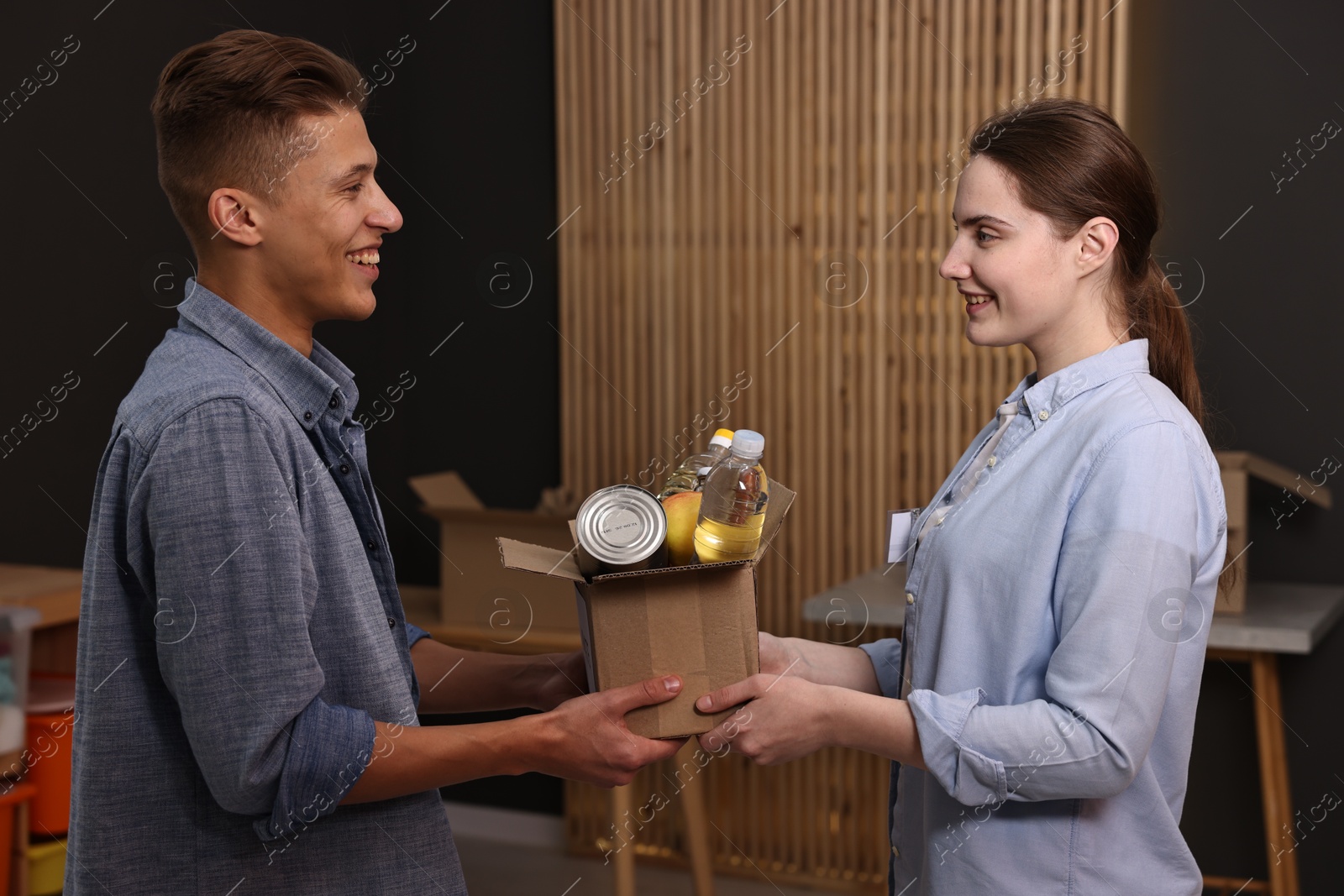 Photo of Volunteers holding donation box with food products indoors