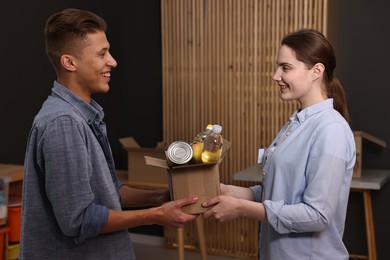 Photo of Volunteers holding donation box with food products indoors