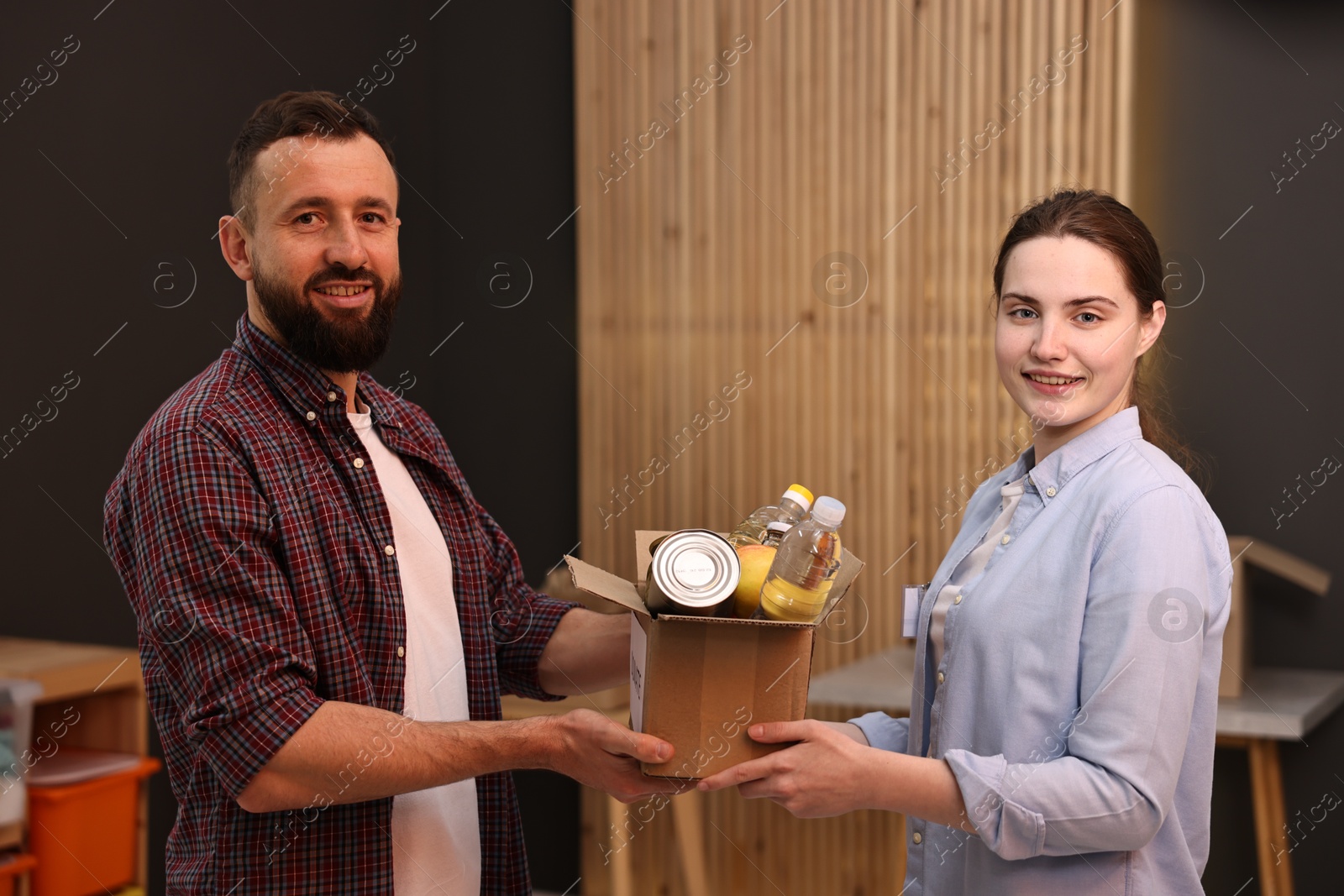 Photo of Volunteers holding donation box with food products indoors